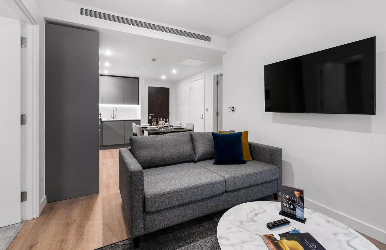 מנצ'סטר Citysuites 2 Aparthotel מראה חיצוני תמונה The photo shows a modern living space that includes a gray sofa with colorful cushions, a round marble coffee table, and a flat-screen TV mounted on the wall. In the background, there is a kitchen area featuring sleek cabinets. The flooring is light 