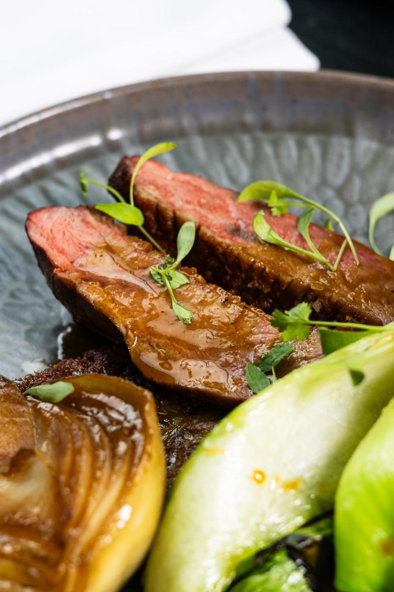 מנצ'סטר Citysuites 2 Aparthotel מראה חיצוני תמונה The photo features slices of meat, likely beef, presented on a decorative plate. The meat appears to have a rich brown sauce drizzled over it and is garnished with fresh herbs, adding a pop of green. There are also some slices of a light-colored vege